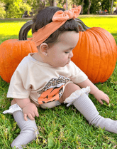 Little girl is wearing a comfortable baby girl head wrap from By Bella Boutique.